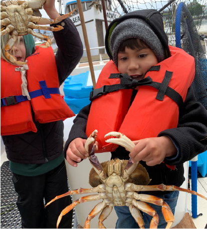 Two young boys holding their king crab catch